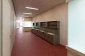 Gang im Schulhaus mit rotem Boden und Holzdecken